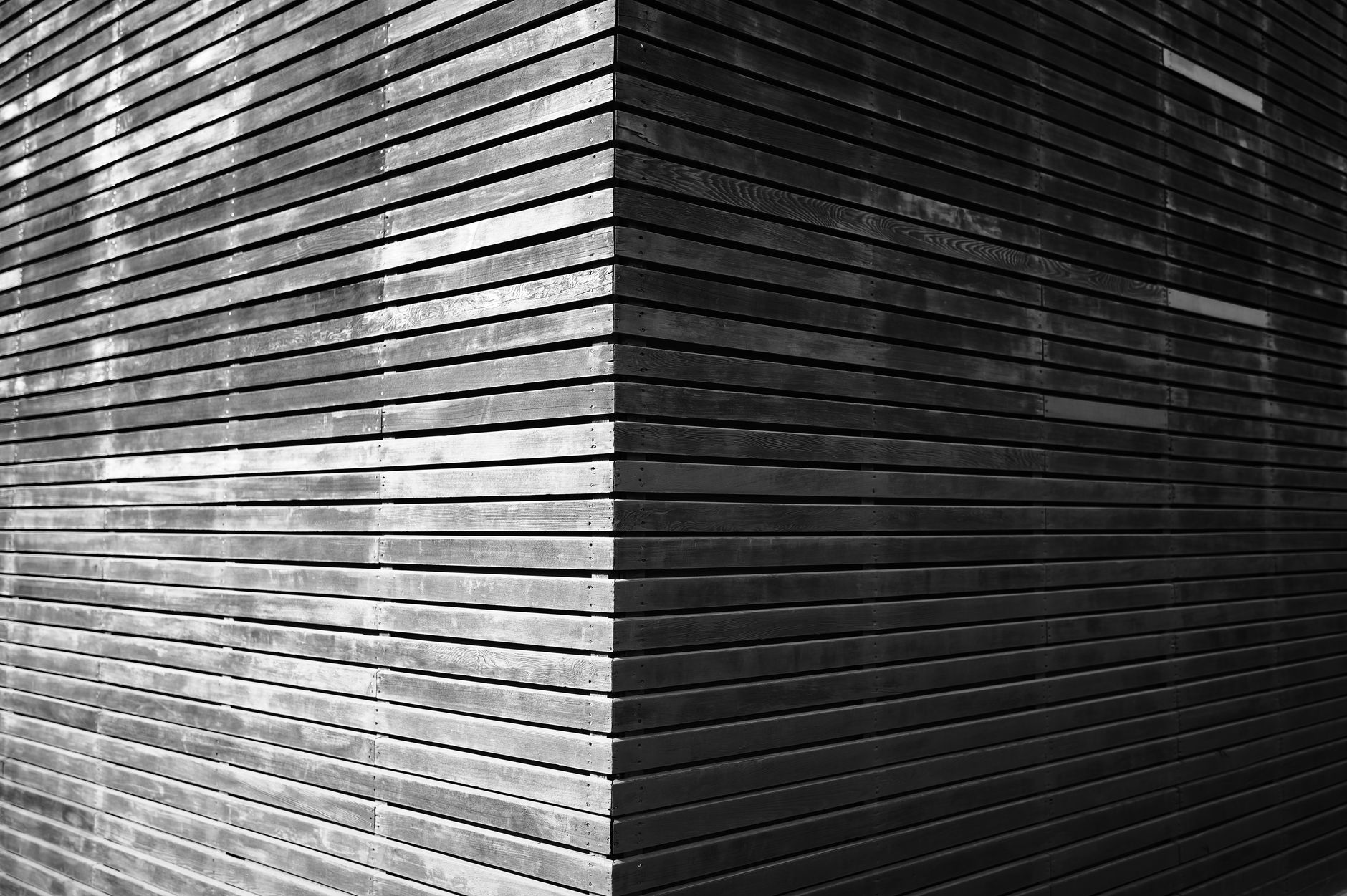 Monochrome image of a corner with horizontal wooden slats, creating a geometric pattern.
