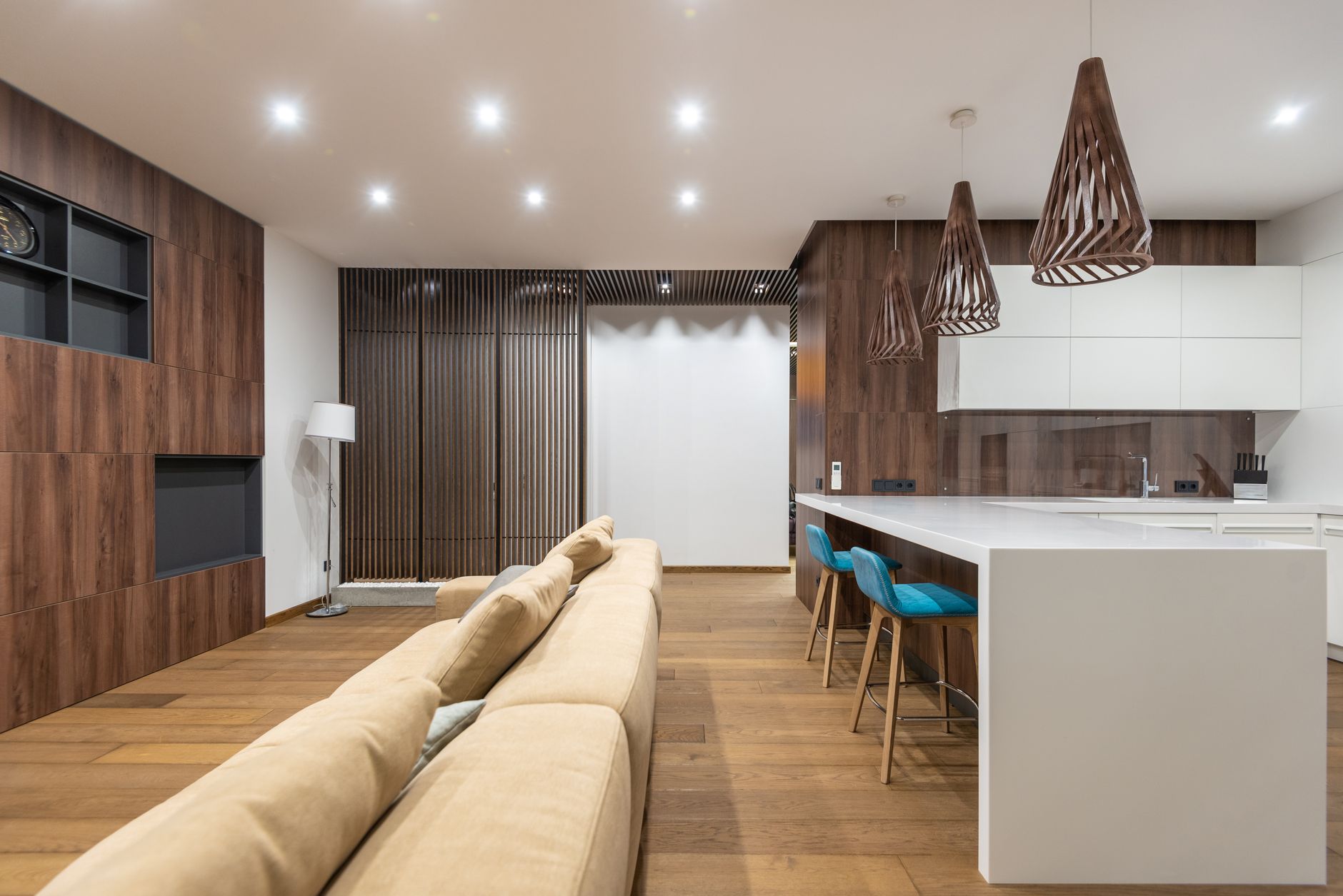 Chairs at white cabinets placed in modern spacious apartment with comfortable sofa near wooden cupboards with black shelves at home
