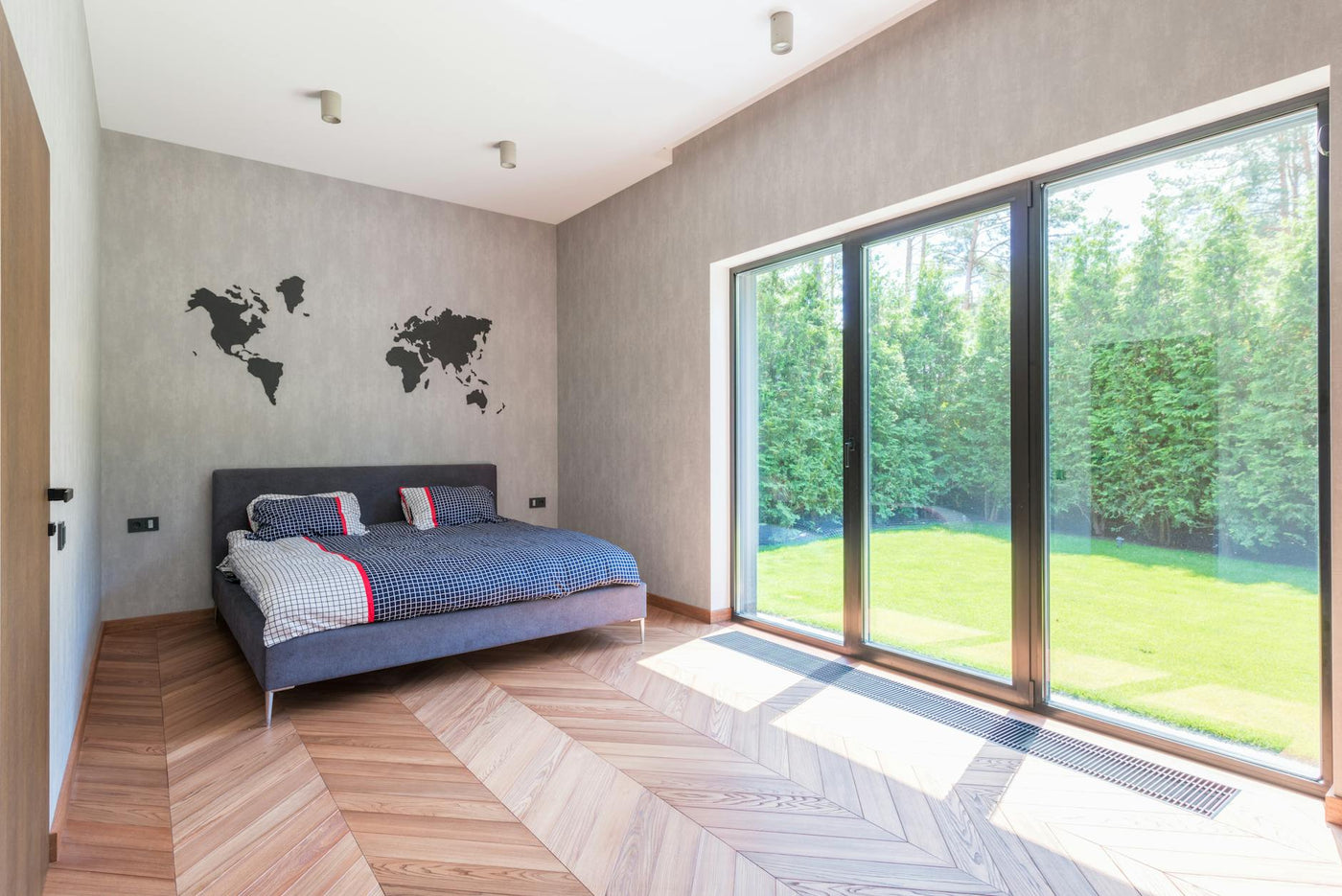 Stylish minimalist bedroom with a bed and sliding glass doors overlooking a garden.
