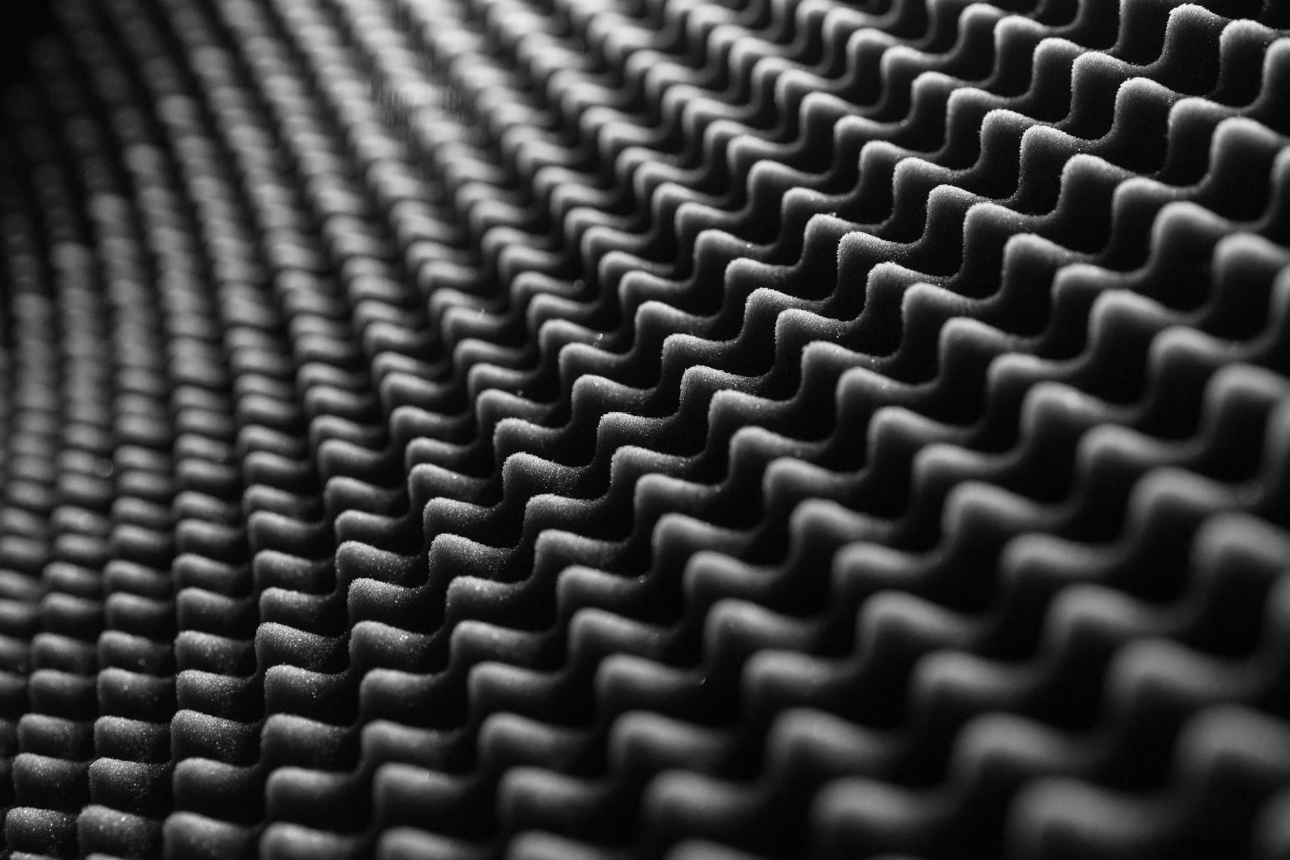 Close-up view of textured soundproof foam in black and white, showcasing its detailed pattern.