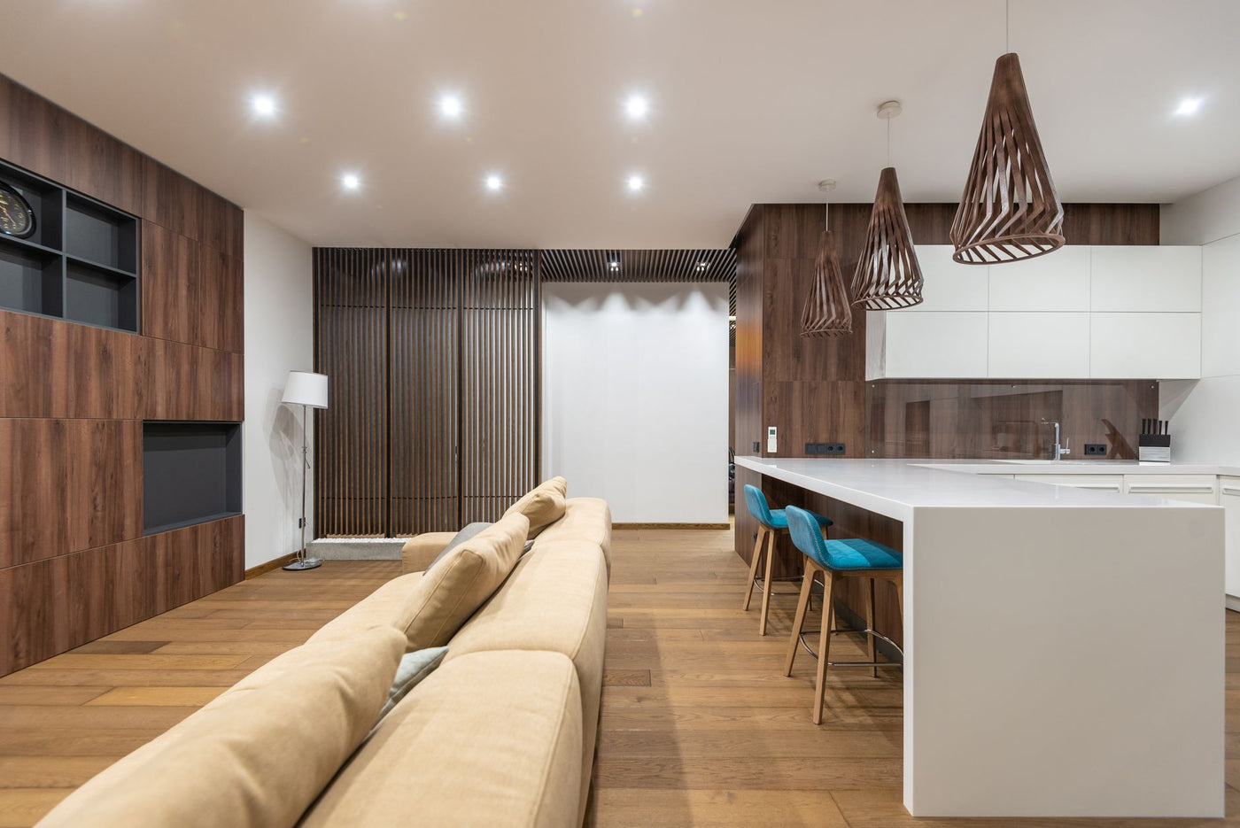 Chairs at white cabinets placed in modern spacious apartment with comfortable sofa near wooden cupboards with black shelves at home
