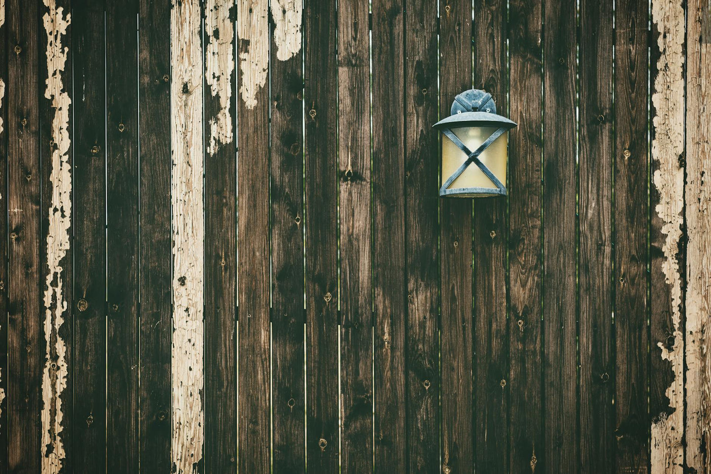A weathered wooden fence with a vintage lantern adding rustic charm.