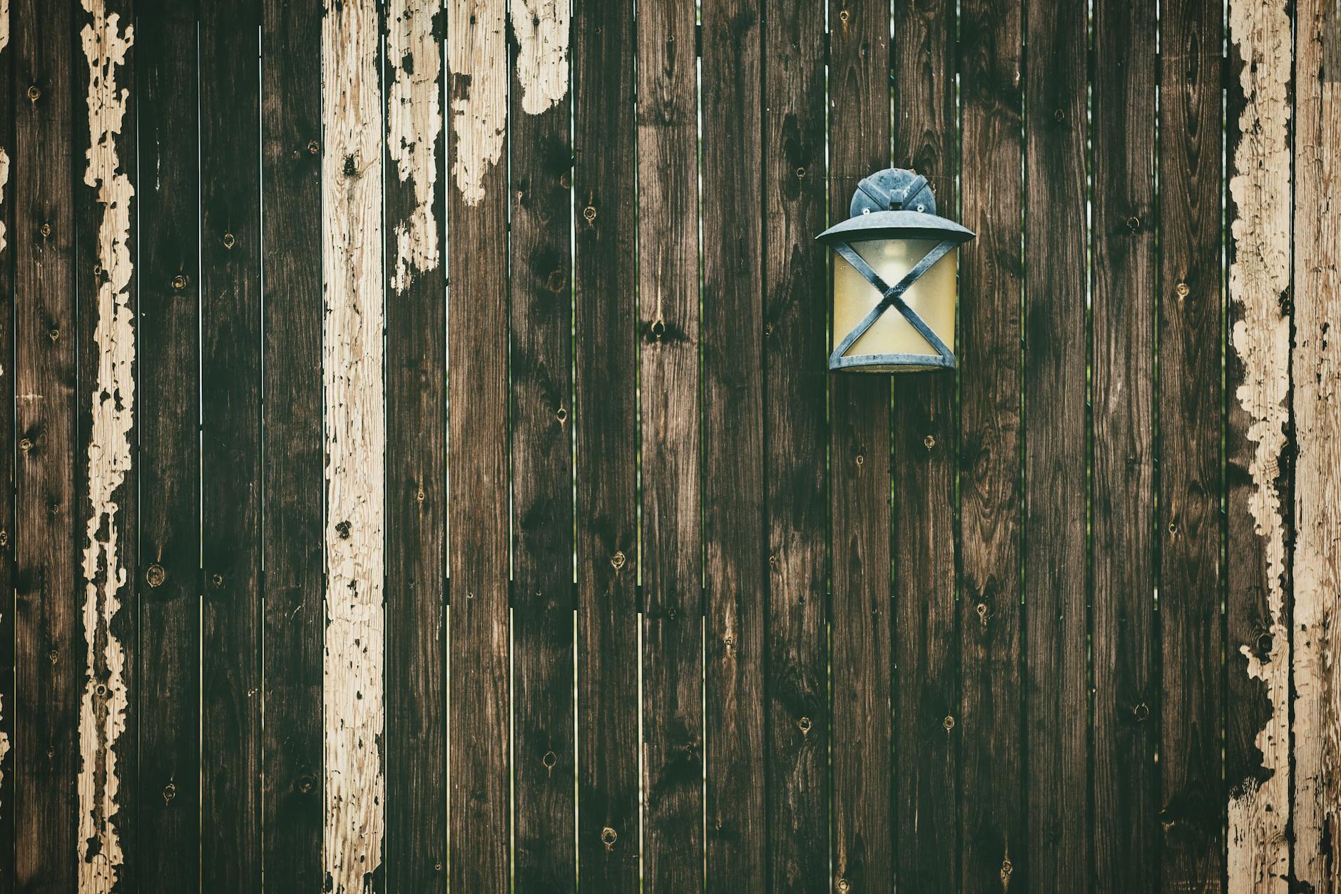A weathered wooden fence with a vintage lantern adding rustic charm.