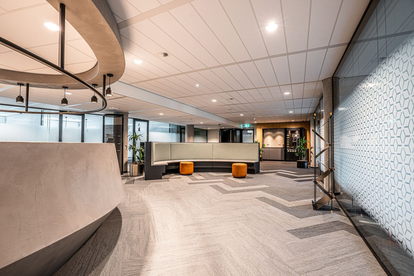 Spacious modern office lobby featuring minimalist interior design with seating and decorative lighting.