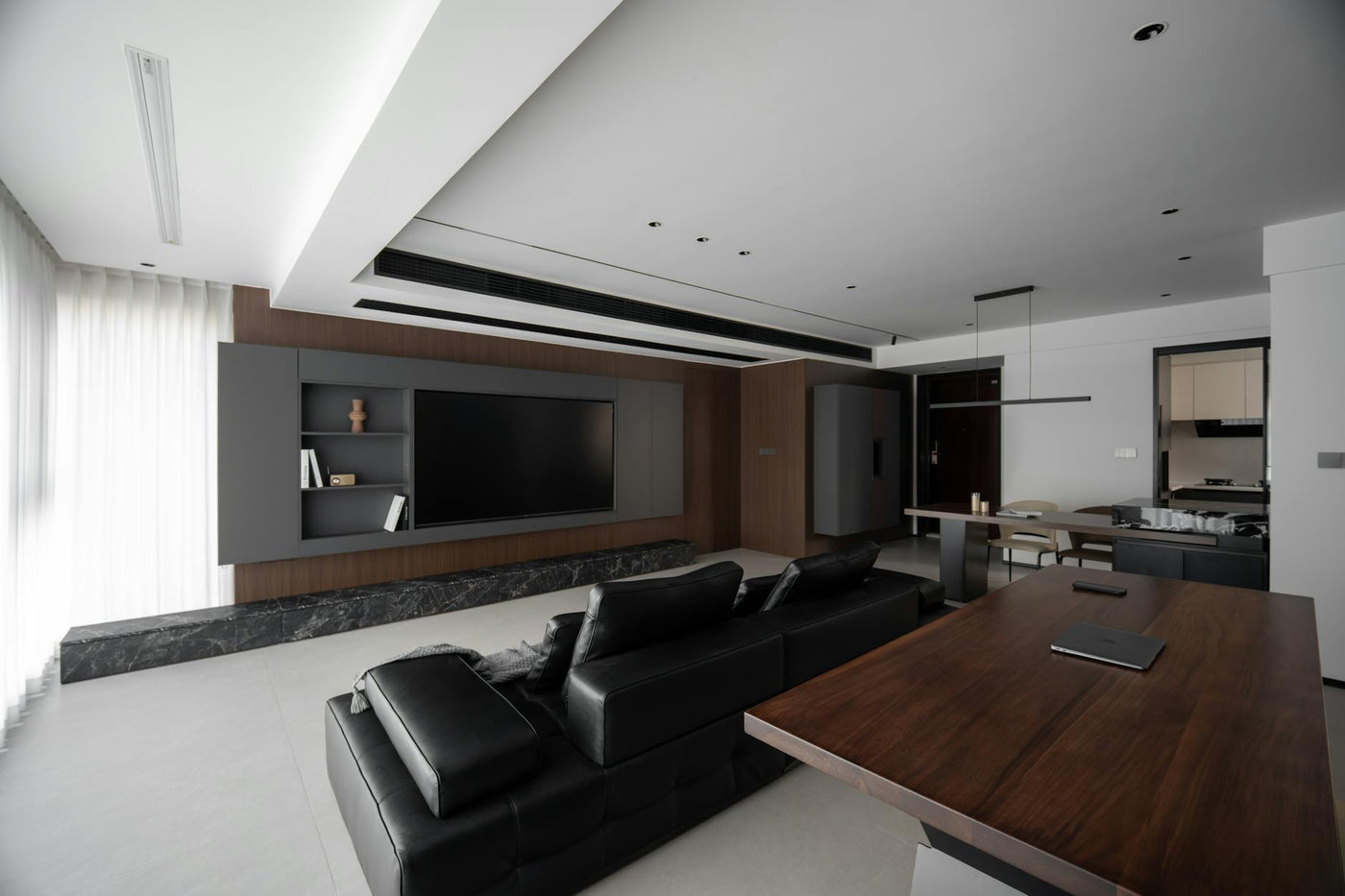 Sleek modern living room featuring black leather sofa and wooden furniture set.