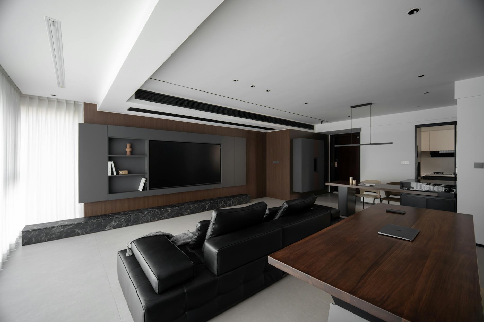 Sleek modern living room featuring black leather sofa and wooden furniture set.