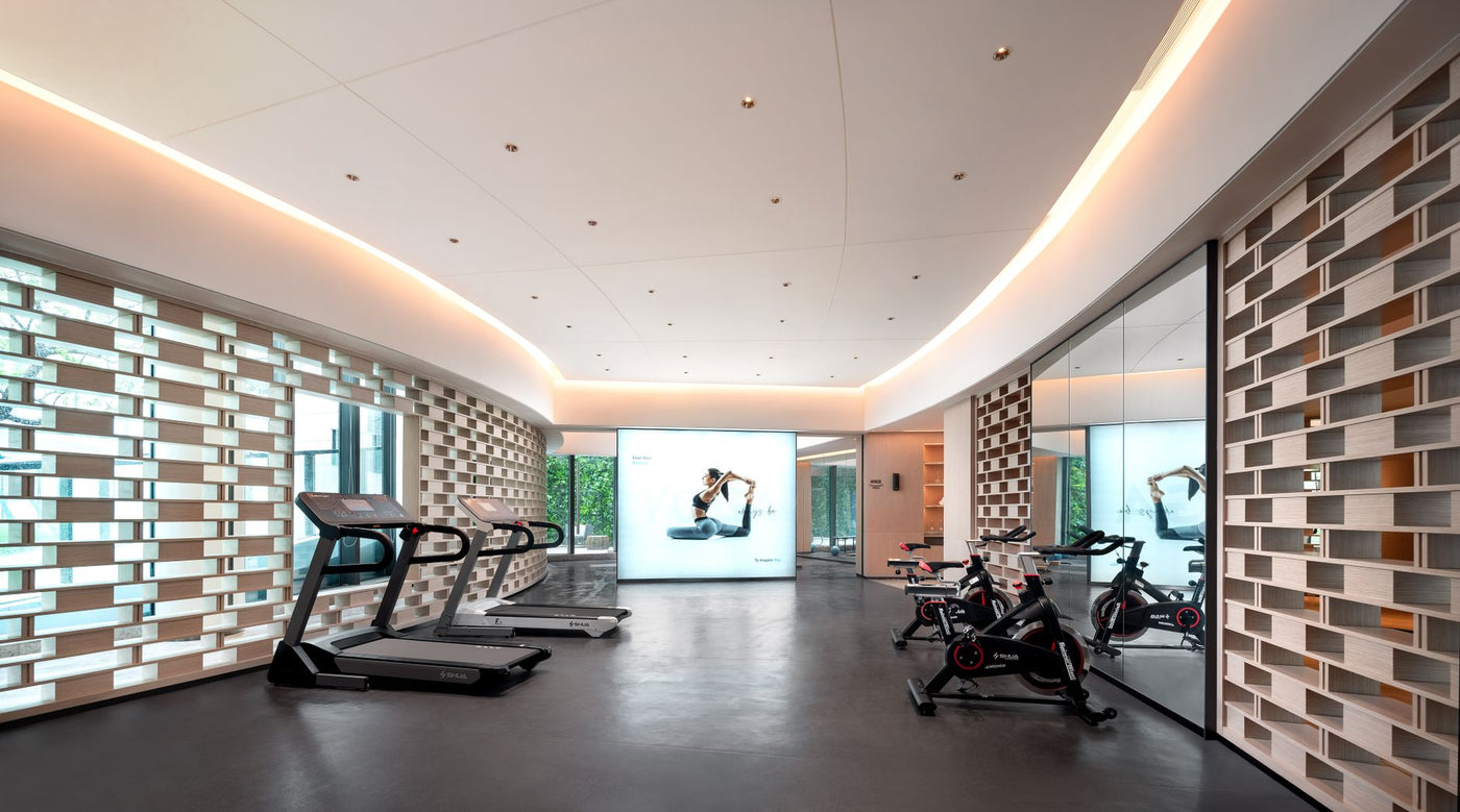 Sleek gym interior with treadmills and stationary bikes, technology-focused design.